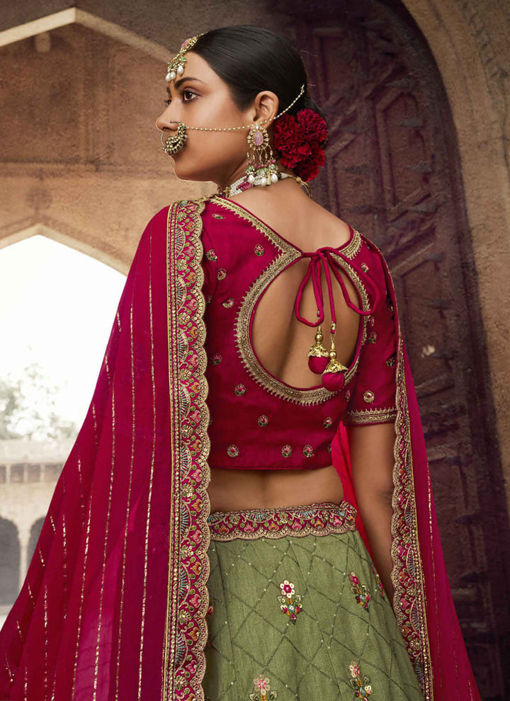 Image: Women in Crimson Red & Olive Green Color Designer Wedding Wear Lehenga Choli with Embroidery Work. The lehenga choli showcases a stunning combination of crimson red and olive green colors. It features exquisite embroidery work, blending traditional and contemporary elements for an elegant look.