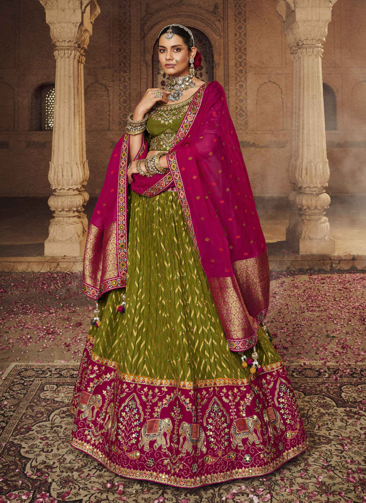 Image: Women in Olive Green Designer Wedding Wear Lehenga Choli with Weaving Work. The lehenga choli features a captivating olive green color and is embellished with intricate weaving work. The weaving patterns add a touch of elegance and sophistication to the ensemble, creating a visually stunning look. This attire is ideal for a wedding or special occasion, radiating grace and style.
