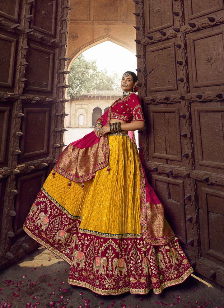 Image: Women in Red & Mustard Yellow Designer Wedding Wear Lehenga Choli with Weaving Work. The lehenga choli showcases a beautiful combination of red and mustard yellow colors. It is adorned with intricate weaving work, creating mesmerizing patterns and textures. This ensemble exudes a vibrant and festive vibe, making it an excellent choice for a wedding or celebratory event.