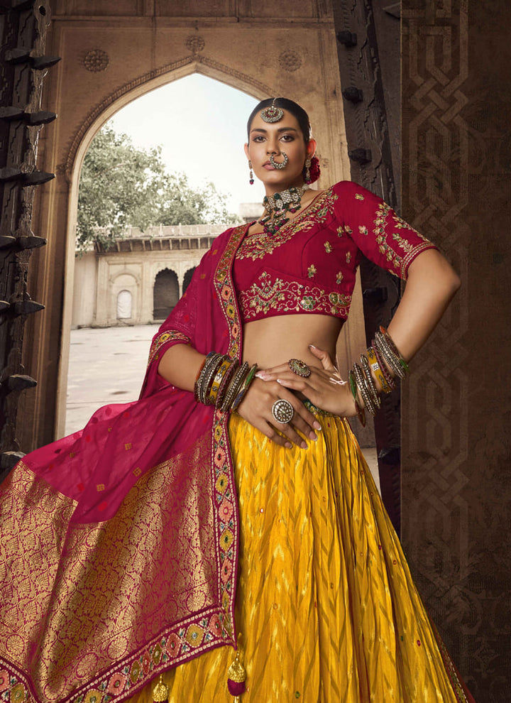 Image: Women in Red & Mustard Yellow Designer Wedding Wear Lehenga Choli with Weaving Work. The lehenga choli showcases a beautiful combination of red and mustard yellow colors. It is adorned with intricate weaving work, creating mesmerizing patterns and textures. This ensemble exudes a vibrant and festive vibe, making it an excellent choice for a wedding or celebratory event.