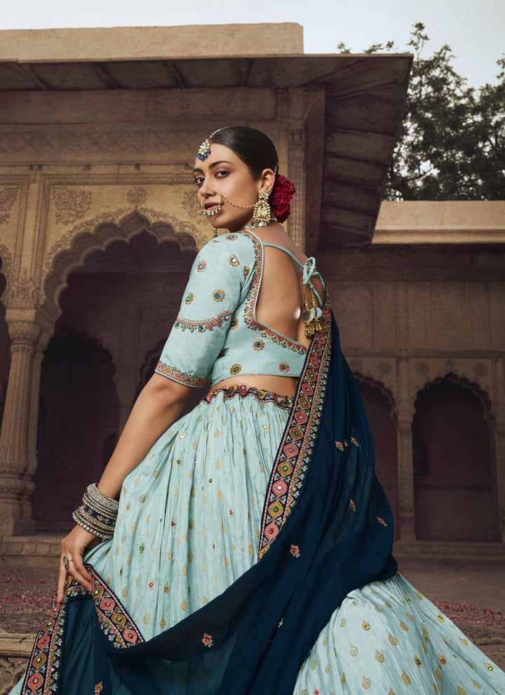 Image: Women in Pale Blue Designer Wedding Wear Lehenga Choli with Weaving Work. The lehenga choli features a rich and elegant purple wine color, accentuated with intricate weaving work. The weaving patterns add depth and texture to the ensemble, creating a captivating and luxurious look. This attire is perfect for a wedding or special occasion, emanating sophistication and glamour.