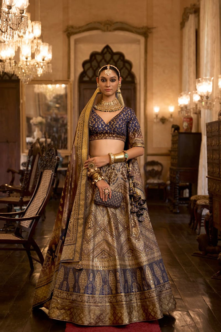 Image: Woman in Beige & Navy Blue Color Sparkling Rajwadi Silk Lehenga with Mirror Work Blouse. This dazzling lehenga ensemble features a beige color, crafted from luxurious Rajwadi silk. The blouse is adorned with intricate mirror work, adding a touch of sparkle and glamour. Perfect for special occasions, this attire radiates elegance and can be found in various Indian clothing stores offering Rajwadi silk lehengas.