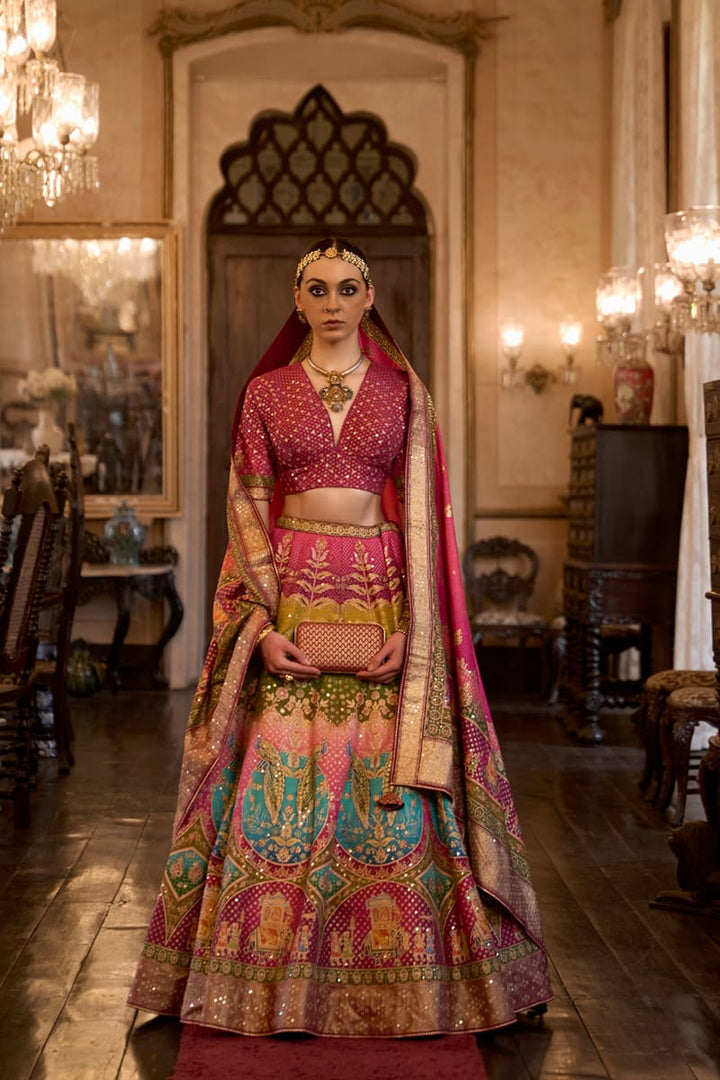 Image: Woman in Pink Color Sparkling Rajwadi Silk Lehenga with Mirror Work Blouse. This dazzling lehenga ensemble features a beige color, crafted from luxurious Rajwadi silk. The blouse is adorned with intricate mirror work, adding a touch of sparkle and glamour. Perfect for special occasions, this attire radiates elegance and can be found in various Indian clothing stores offering Rajwadi silk lehengas.