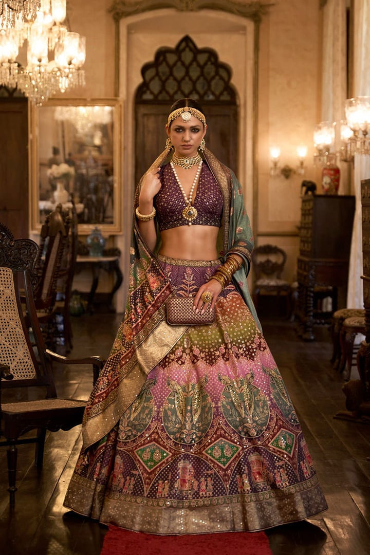 Image: Woman in Purple Color Sparkling Rajwadi Silk Lehenga with Mirror Work Blouse. This dazzling lehenga ensemble features a beige color, crafted from luxurious Rajwadi silk. The blouse is adorned with intricate mirror work, adding a touch of sparkle and glamour. Perfect for special occasions, this attire radiates elegance and can be found in various Indian clothing stores offering Rajwadi silk lehengas.