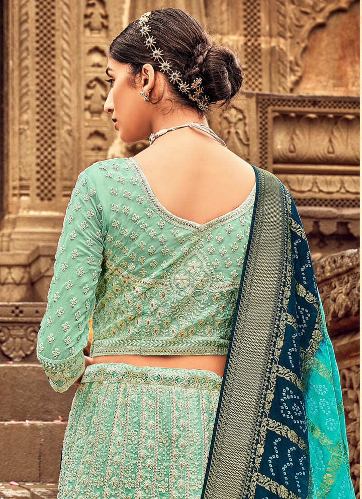 Woman in Sea green Elegant Designer Lehenga Cholis with Lakhnavi Work. This exquisite ensemble showcases a delightful cream color and is adorned with intricate Lakhnavi work. The designer lehenga choli exudes elegance and charm, making it a perfect choice for weddings and special occasions. With its stunning craftsmanship and graceful appeal, this outfit is sure to make the wearer stand out with sophistication and style.