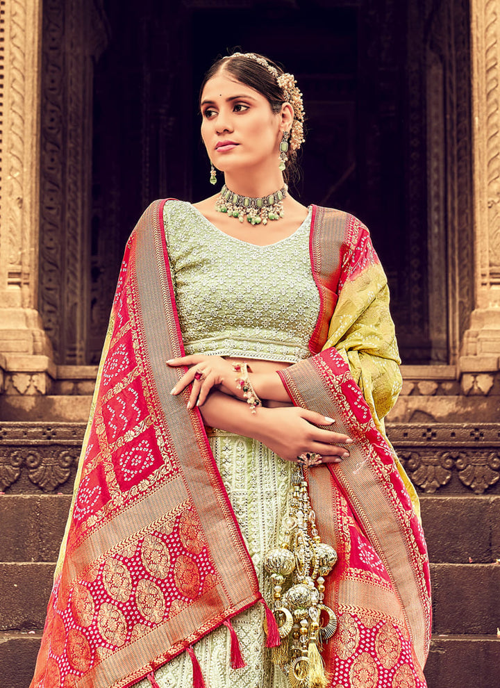 Woman in Pista green Elegant Designer Lehenga Cholis with Lakhnavi Work. This exquisite ensemble showcases a delightful cream color and is adorned with intricate Lakhnavi work. The designer lehenga choli exudes elegance and charm, making it a perfect choice for weddings and special occasions. With its stunning craftsmanship and graceful appeal, this outfit is sure to make the wearer stand out with sophistication and style.