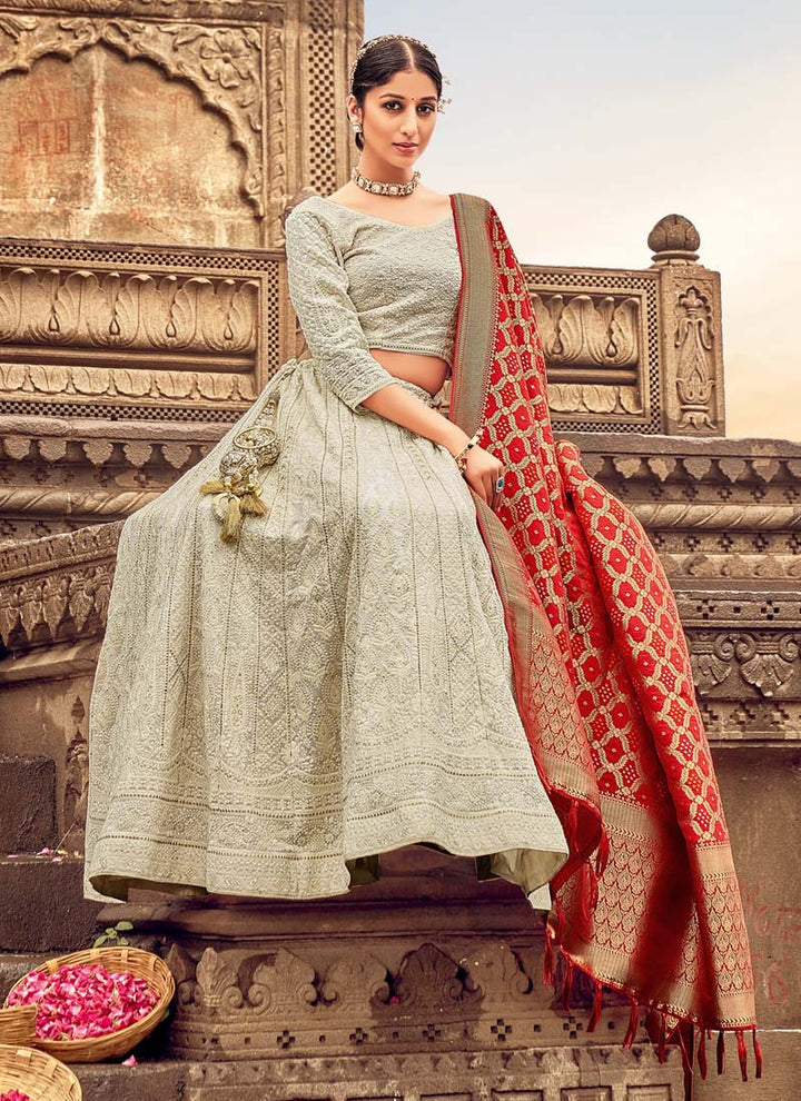 Woman in Grey Elegant Designer Lehenga Cholis with Lakhnavi Work. This exquisite ensemble showcases a delightful cream color and is adorned with intricate Lakhnavi work. The designer lehenga choli exudes elegance and charm, making it a perfect choice for weddings and special occasions. With its stunning craftsmanship and graceful appeal, this outfit is sure to make the wearer stand out with sophistication and style.